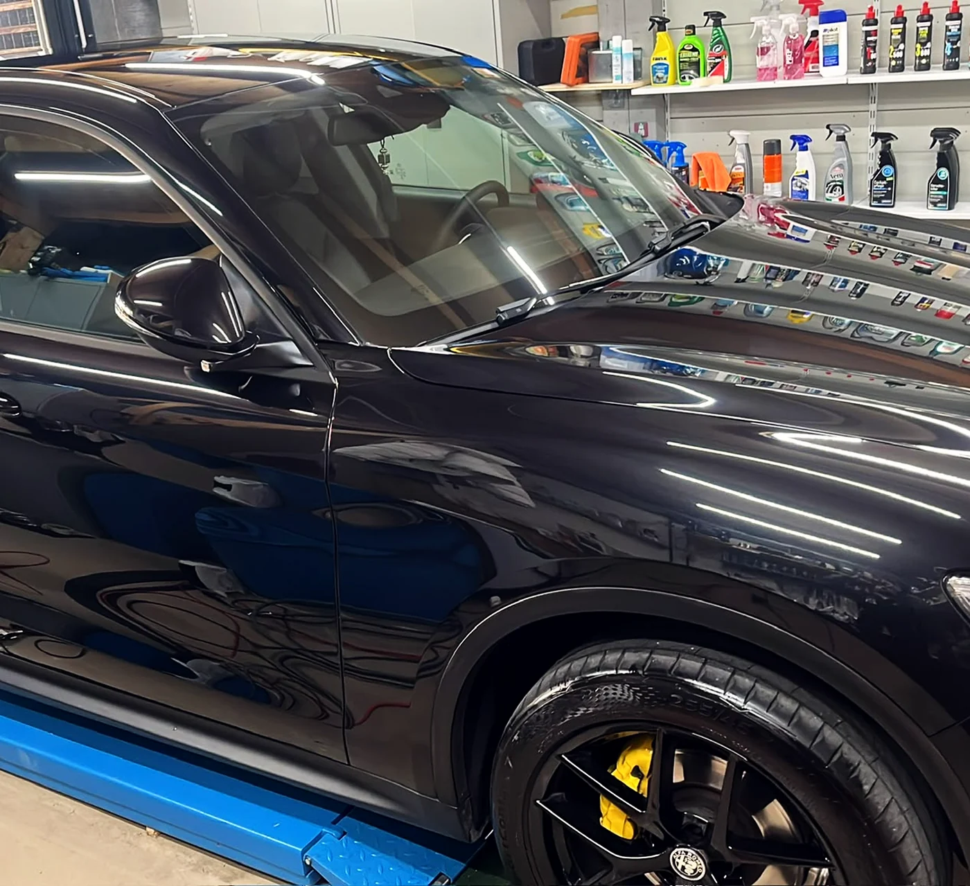 Schwarzer Alfa Romeo Stelvio in der Werkstatt in Schaan, die Flanke spiegelt nach der Lackaufbereitung gleichmässig