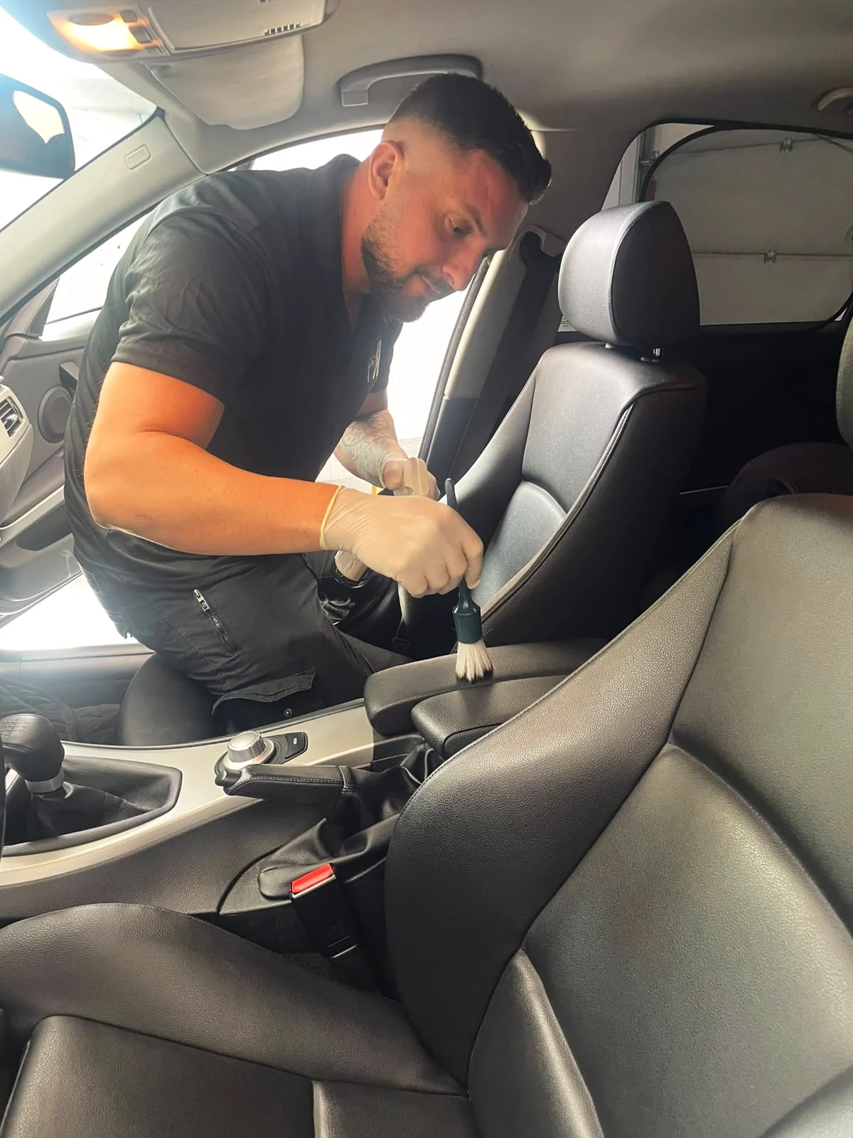 Florent Musliu reinigt den Innenraum eines Fahrzeugs mit einem Pinsel, Axiom-Polish in Schaan