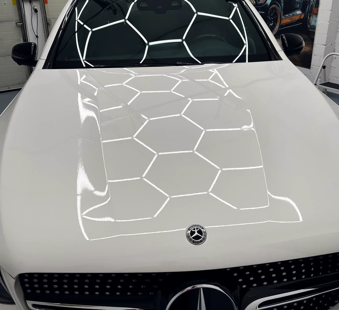 Motorhaube eines weissen Mercedes GLC, die Deckenbeleuchtung der Werkstatt in Schaan spiegelt sich gleichmässig im Lack