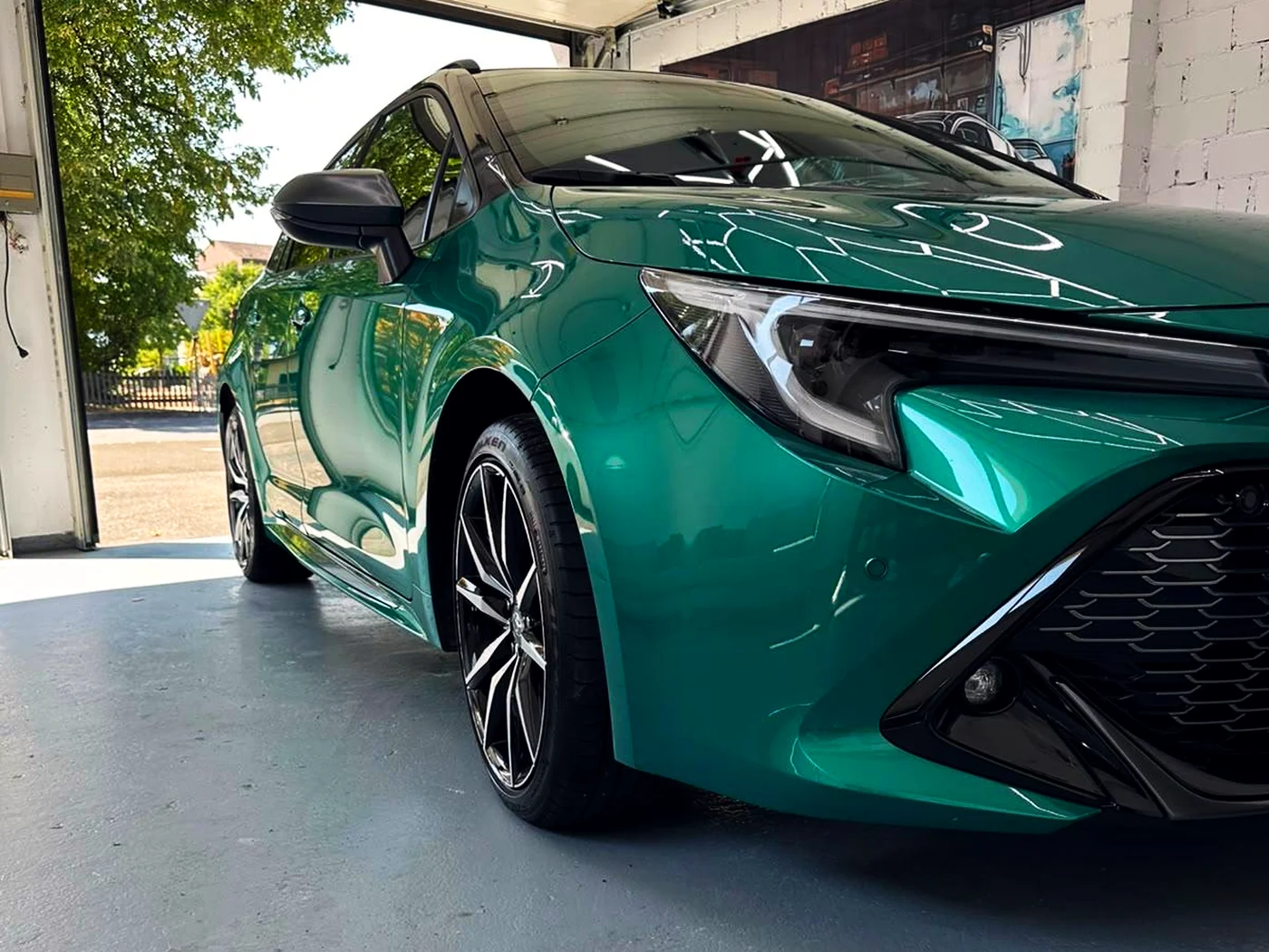 Grüner Toyota Corolla, fertig aufbereitet im Tor der Werkstatt in Schaan